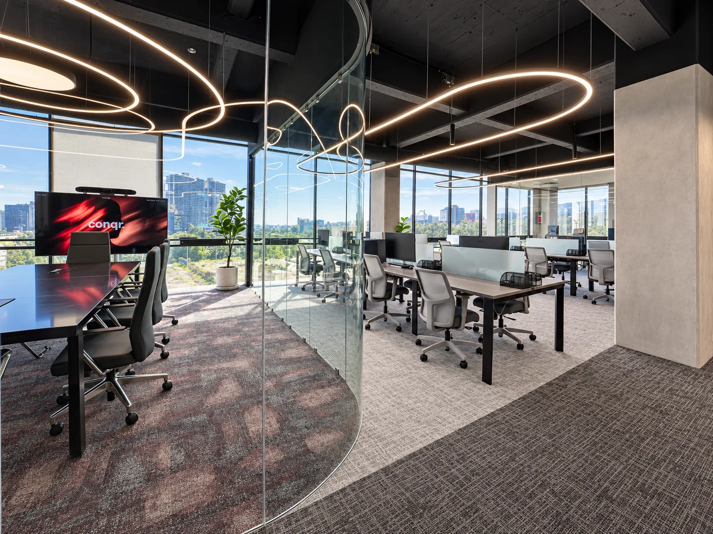 Curved glass meeting room and workstations with a view of the city