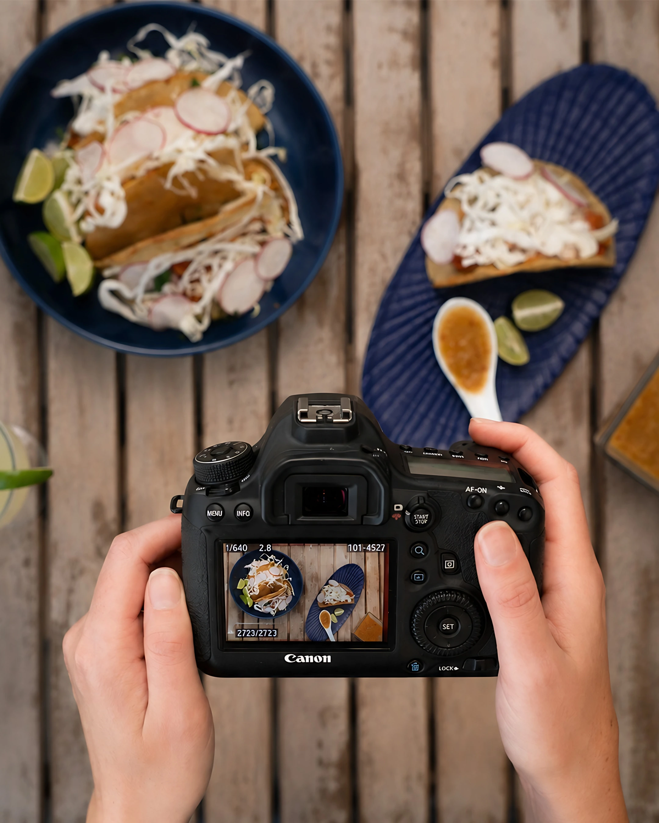 Hands holding a camera over a table with tostadas, showing the shot on screen