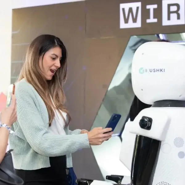 Woman using her phone next to a robot at a WIRED event stand
